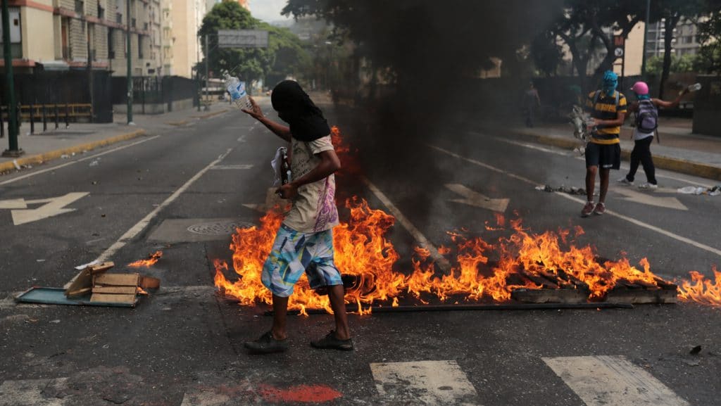 Anti-government protesters oversee a burning barricade in Caracas, Venezuela, Monday, June 26, 2017. Protesters have flooded the streets of Venezuela for months, demanding new elections and faulting President Nicolas Maduro's leadership for the country's triple-digit inflation, surging crime rates, and dire shortages of food and medicine. (AP Photo/Fernando Llano)