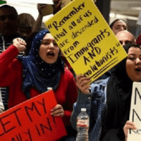 Dozens of pro-immigration demonstrators cheer and hold signs as international passengers arrive at Dulles International Airport. | Photo: Reuters