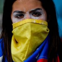 An anti-government protester covers her face with a Venezuelan flag