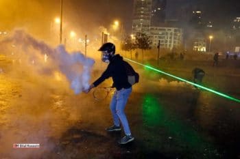 An anti government protester throwing back a tear gas canister