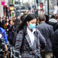 A pedestrian wears a surgical mask on a busy street in mid-town Manhattan, as concerns grow around COVID-19, Tuesday March 3, 2020, in New York. A man from New York City's suburbs was hospitalized in serious condition with COVID-19 on Tuesday, a case that prompted school closings and quarantines for congregants of a now-shuttered synagogue. The state's second confirmed case also raised the possibility that the virus is spreading locally. (AP Photo/Bebeto Matthews)