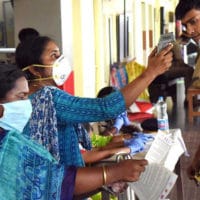 Medical officers measure body temperature of passengers at a railway station in Kochi (state of Kerala) on March 16