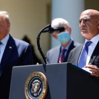 President Donald Trump, left, listens as Moncef Slaoui, a former GlaxoSmithKline executive, speaks about the coronavirus in the Rose Garden of the White House, Friday, May 15, 2020, in Washington. (AP Photo/Alex Brandon)