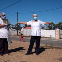 8 May 2020: As part of South Africa’s community screening and testing programme, a Khayelitsha Eastern community team tests farm workers in Faure, where a number of positive cases were discovered. A health worker signals what the minimum social distance should be. Barry Christianson / New Frame
