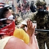 A federal officer pushes back demonstrators at the Mark O. Hatfield United States Courthouse on Tuesday, July 21, 2020, in Portland, Ore. (AP Photo/Noah Berger)