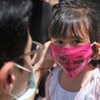 A father helps his child with a mask in front of Bradford School in Jersey City, New Jersey on June 10, 2020 (AP Photo/Seth Wenig, File)