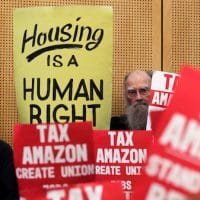 Members of the public look on at a Seattle City Council before the council voted to approve a tax on large businesses such as Amazon and Starbucks to fight homelessness in Seattle. Elaine Thompson | AP