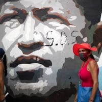 Government supporters walk past a mural depicting the late president Hugo Chavez during a closing campaign rally for the upcoming parliamentary elections, in Caracas, Venezuela, Thursday, Dec. 3, 2020. The South American nation is caught in a deepening political and economic crisis, despite holding the world's largest oil reserves. (AP Photo/Ariana Cubillos)