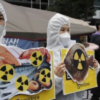 Environmental activists wearing a mask of Japanese Prime Minister Yoshihide Suga and protective suits perform to denounce the Japanese government's decision on Fukushima water, near the Japanese embassy in Seoul, South Korea
