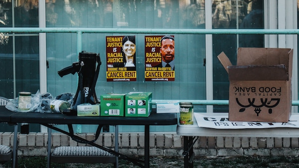| Two posters with messages for DC Council members Pinto and McDuffie behind supply tables at the rally Eleanor Goldfield | ArtKillingApathycom | MR Online
