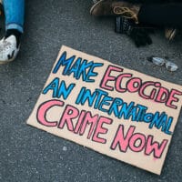 "Make Ecocide An International Crime Now" sign on the tarmac at a rally against climate change
