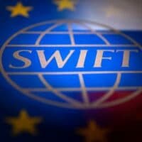 Swift logo is pictured with EU and Russian flags in this illustration picture taken February 26, 2022.