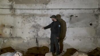 Ilya Podkolzin points to a wall where bullets were fired just past prisoners who believed they were being executed