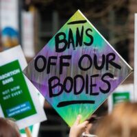 Colourful protest sign that says "Bans off our bodies" Credit: SHYCITYNikon / flickr