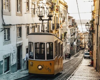 Yellow tram carriage suspended at the top of a narrow street with traditional architecture, Lisbon, Portugal.