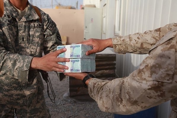 MR Online | US Marine Corps Cpl David Che right a supply warehouse clerk with Headquarters and Service Company 1st Marine Logistics Group Forward hands Afghan currency to Army 1st Lt Manuel Jimenez April 7 2014 | MR Online