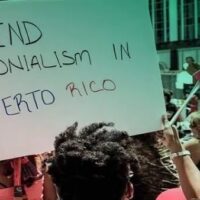 | Protesters in Puerto Rico raise a banner demanding an end to US colonization of the island Photo Progressive International | MR Online