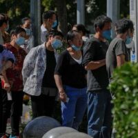Residents wearing face masks line up to get their routine COVID-19 throat swabs at a coronavirus testing site in Beijing, Thursday, Sept. 22, 2022. (AP Photo/Andy Wong)