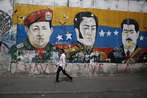 A man walks past a mural depicting Venezuela’s late President Hugo Chávez, Latin American independence hero Simon Bolivar and Venezuela’s President Nicolás Maduro in Caracas. Photo by Marco Bello.