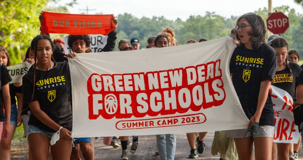 MR Online | Young organizers hold up a banner celebrating the Green New Deal for Schools Summer Camp 2023 Photo Sunrise Movement | MR Online