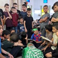 Students gather around the body of their school teacher, Allam Jaradat, who was killed by Israeli forces in Jenin in the occupied West Bank, 21 May 2024 (Reuters/Ali Sawafta)