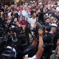 MEMBERS OF THE PALESTINIAN RESISTANCE HOLD THEIR WEAPONS DURING A MEMORIAL SERVICE FOR MOHAMMED AL-AZIZI AND ABDUL RAHMAN SOBH, WHO WERE KILLED BY ISRAELI FORCES IN JULY 2022, IN THE WEST BANK CITY OF NABLUS. (PHOTO: SHADI JARAR’AH/ APA IMAGES)