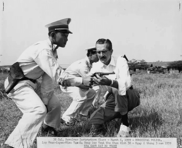 An Michigan State University Group adviser instructor helps a Vietnamese municipal police officer on his technique with a 38 caliber revolver March 6 1959 Source politicocom