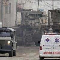 Israeli military vehicles guard a road where a military bulldozer operates in the West Bank refugee camp of Jenin, January 22, 2025. [AP Photo/Majdi Mohammed]