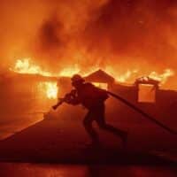 A firefighter battles the Palisades Fire as it burns a structure in the Pacific Palisades neighbourhood of Los Angeles, January 7, 2025