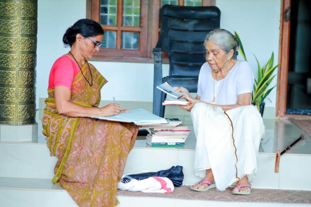 Radha V P in her village in Vellur Kannur Kerala with her bag of books from the Jawahar Library