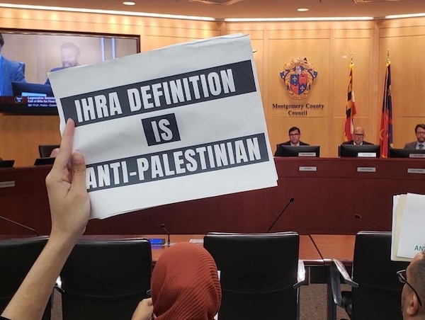  | AN ACTIVIST HOLDS UP A SIGN AT A MONTGOMERY COUNTY COUNCIL MEETING ON OCTOBER 25 PROTESTING THE COUNCILS CONSIDERATION TO ADOPT THE IHRA DEFINITION OF ANTISEMITISM PHOTO MARYLAND 2 PALESTINETWITTER | MR Online