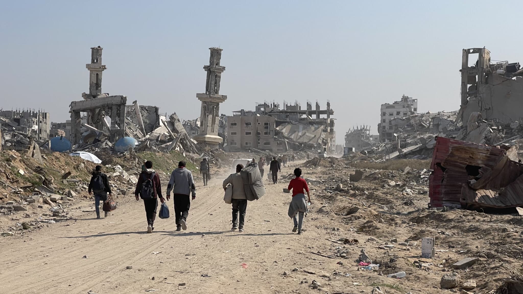 MR Online | Refugees walk down a road in Gaza surrounded by ruined buildings | MR Online