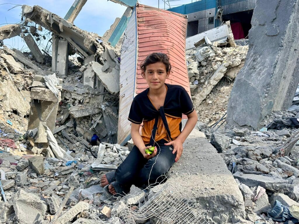 2322783d5dd6495888ae3d4af9e1afa63494x2622 | MR Online ala Ghassan Al Masri 13 sits on the rubble of an UNRWA building in Jabaliya refugee camp that was bombed by the Israeli military May 10 2025 Photo by Hamza Salha