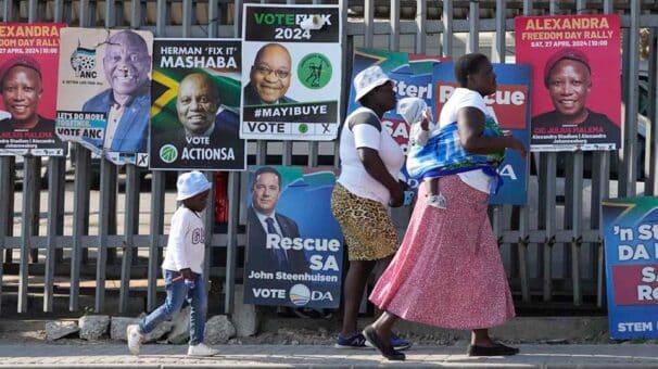 SouthAfricavotes2024606x340 | MR Online Women with children walk past election posters in Tembisa east of Johannesburg South Africa May 28 2024 The results of the vote forced the ANC into a fragile coalition with several conservative and right wing parties | Themba Hadebe AP