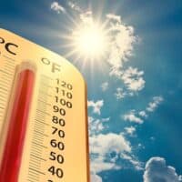 climate change, low angle view Thermometer on blue sky with sun shining in summer show increase temperature, concept global warming
