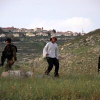 SETTLER FROM THE HAR BRACHA SETTLEMENT THROWS STONES AT PALESTINIAN VILLAGERS FROM BURIN UNDER PROTECTION OF THE ISRAELI ARMY, APRIL 19, 2011.(PHOTO: WAGDI ESHTAYAH/APA IMAGES)