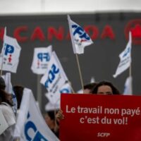 Flight attendants protest in front of the Air Canada headquarters in Montreal, Canada, holding a sign that says: ‘Work without pay is theft.’