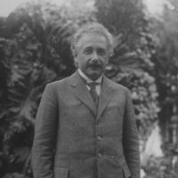 A black and white photo of Albert Einstein against a background of trees.