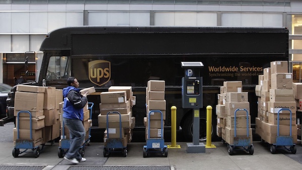 A UPS driver unloads packages from a truck and arranges them for delivery. [AP Photo/Mark Lennihan]