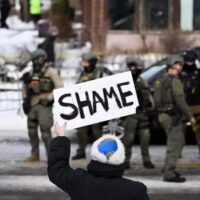 A protester holds a sign reading ‘shame’ at the scene of the shooting in Minneapolis PHOTO: Stephen Maturen/AFP
