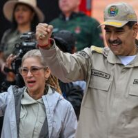 Cilia Flores and President Nicolás Maduro raise their fists together at a public event in Caracas. Flores, a longtime political leader who has described herself as the “First Revolutionary Combatant,” was seized alongside Maduro during the U.S. invasion of Venezuela on Jan. 3, 2026.