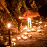 Lena lights a candle at a growing memorial site at 26th Street West and Nicollet Avenue, where federal agents shot and killed 37-year-old Alex Pretti Saturday, Jan. 24, 2026 earlier in the day. (Photo by Nicole Neri/Minnesota Reformer)