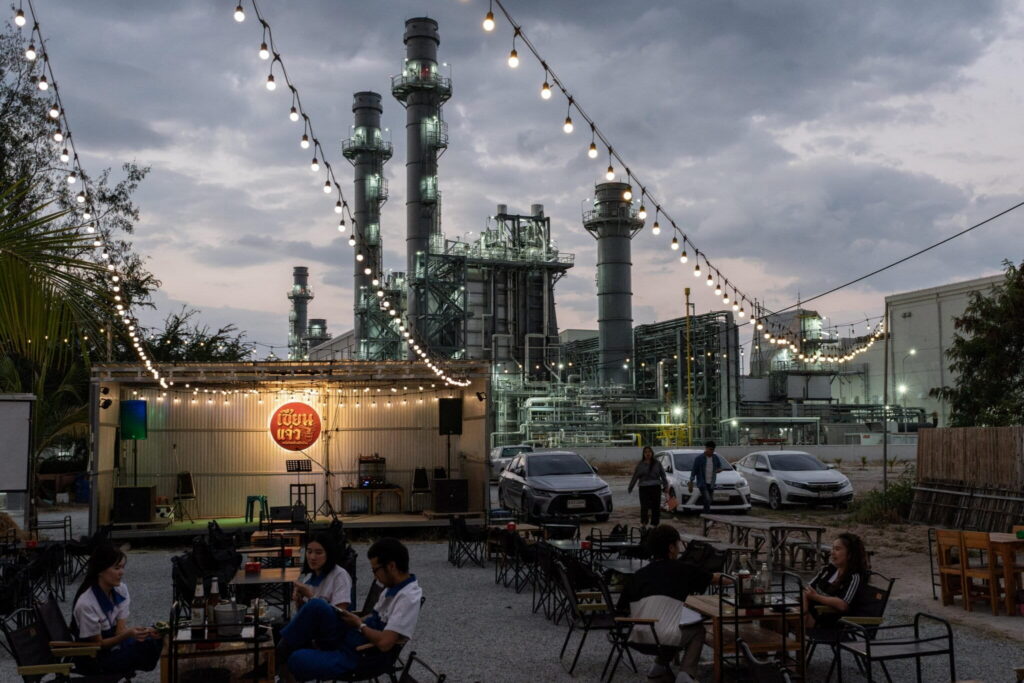 People eat dinner at a restaurant in front of a factory in Amata City Chonburi, Chonburi province, Thailand in February 2026. Amata City Chonburi is an industrial estate with more than 800 factories and businesses. Photo by Andy Ball for Mongabay.
