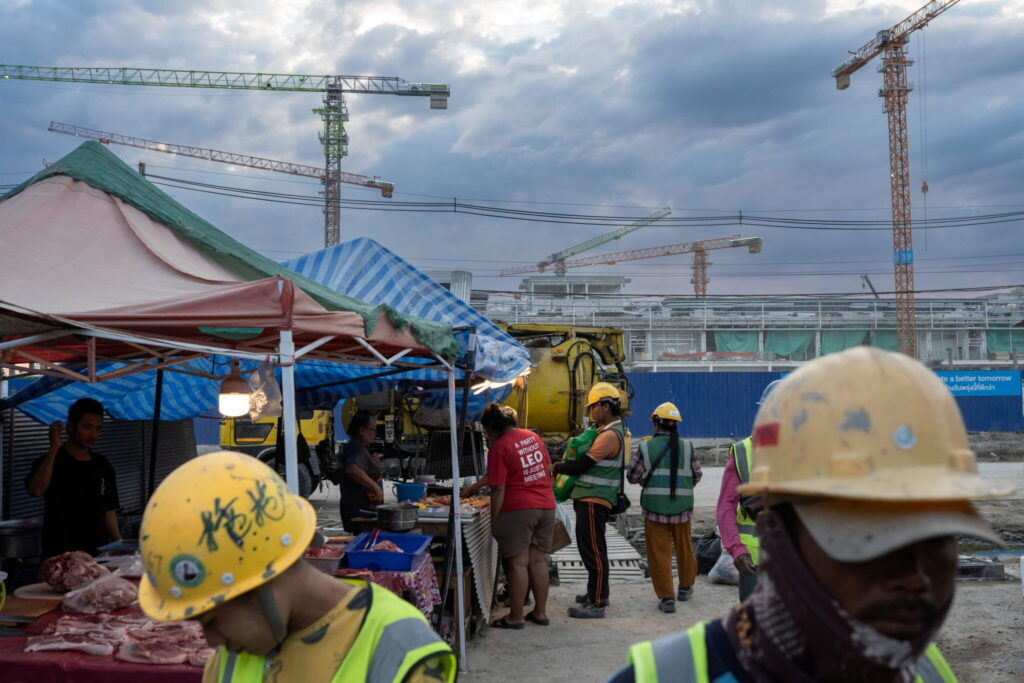 Construction workers hired to build a data center in Chonburi buy food at a market after work. Photo by Andy Ball for Mongabay.