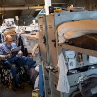An incarcerated man sits in his wheelchair, reading a newspaper in his cell block at California State Prison, Solano in Vacaville, California, in 2013. ANDREW BURTON/GETTY IMAGES