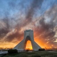 Smoke billows over Tehran behind the Azadi Tower amid Israeli and US bombardment. Photo by Davoid Ghahrdar.