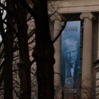 A banner of President Donald Trump is hung on the Department of Justice in February. The Justice Department is arguing it needs access to states’ voter data to ensure the security of the midterm elections. (Photo by Heather Diehl/Getty Images)
