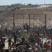 Palestinians gather to receive aid from a GHF aid distribution point at the so-called "Netzarim corridor" in the central Gaza Strip on July 30, 2025. Photo by EYAD BABA/AFP via Getty Images.