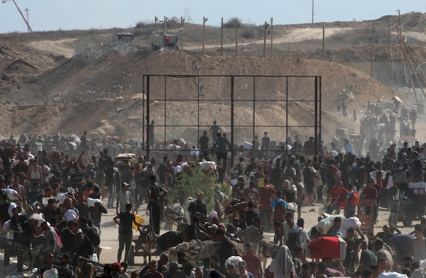 Palestinians gather to receive aid from a GHF aid distribution point at the so-called "Netzarim corridor" in the central Gaza Strip on July 30, 2025. Photo by EYAD BABA/AFP via Getty Images.