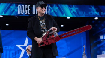 Elon Musk holds a chainsaw as he arrives to speak at the Conservative Political Action Conference, Feb. 20, 2025. Musk’s DOGE didn’t end up finding much waste, but it did cut hundreds of thousands of jobs. | Jose Luis Magana / AP